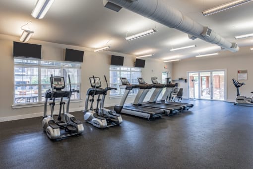 a gym with cardio machines and windows in a building