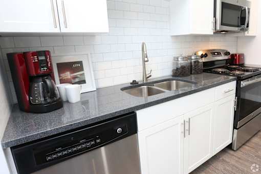 A modern kitchen with a black dishwasher and white cabinets.