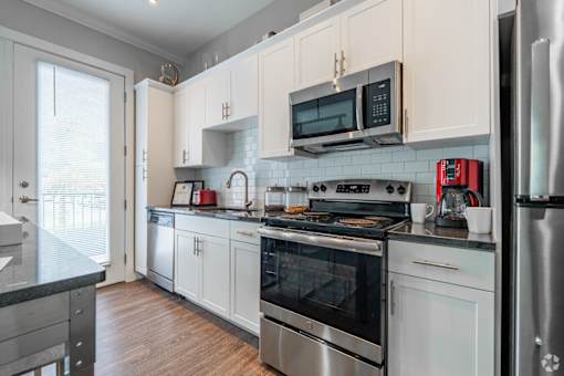 A kitchen with white cabinets and stainless steel appliances.