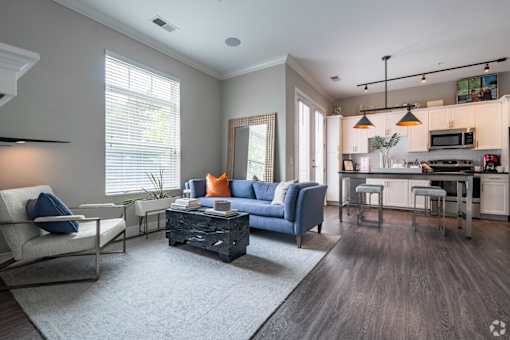 A modern living room with a blue sofa and a grey rug.