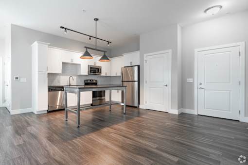 A modern kitchen with a wooden floor and white walls.
