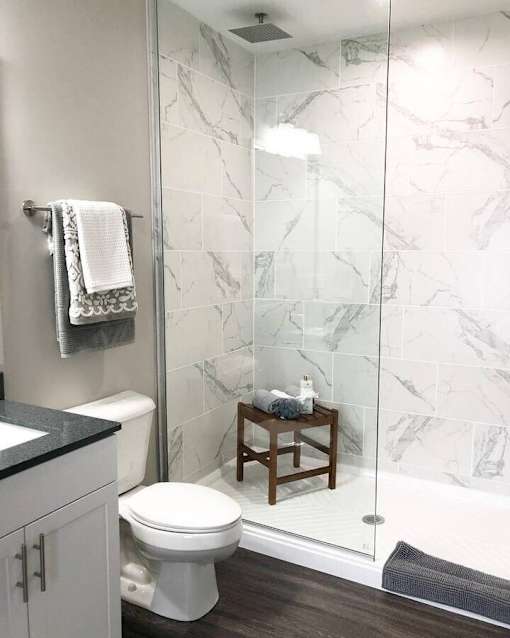 A white toilet sits next to a marble wall in a bathroom.