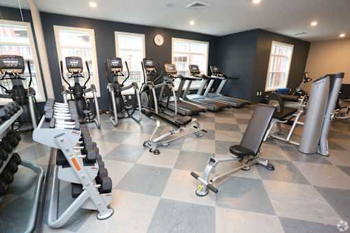 A gym with treadmills, elliptical machines, and weights.