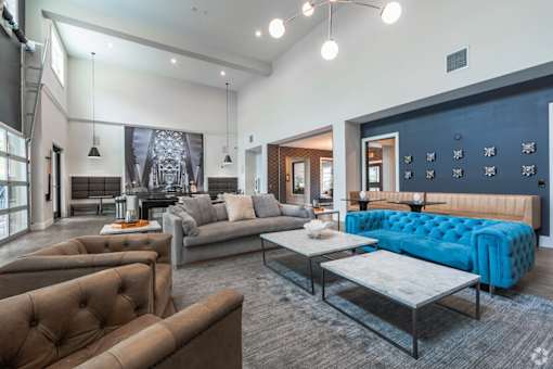 A modern living room with a blue tufted couch and brown velvet chairs.