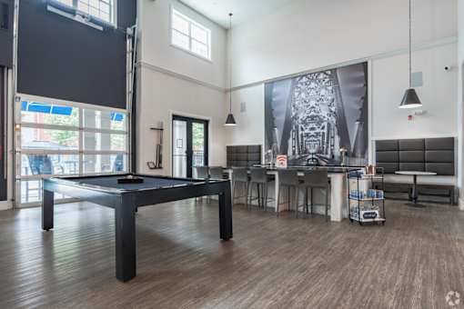 A room with a pool table and a bar area.