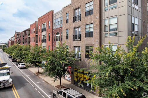 A street view of a row of buildings with cars parked on the side of the road.