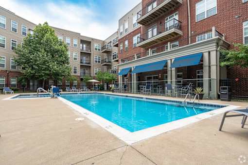 A swimming pool in front of a brick building with a blue awning.