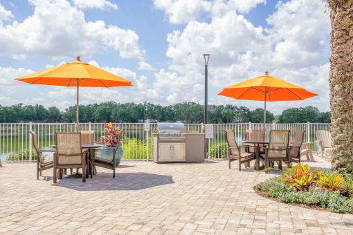 an outdoor patio with tables and umbrellas and a grill