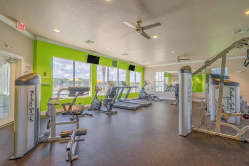 a gym with weights and cardio machines and windows