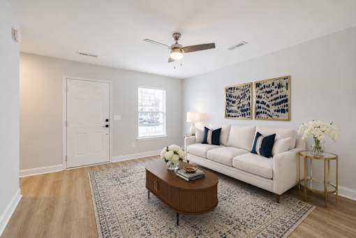 A living room with a white couch, a coffee table, and a ceiling fan.