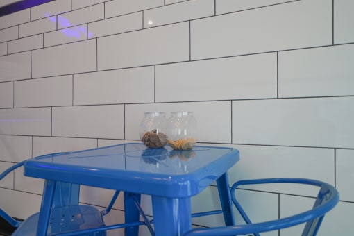 a blue table and two blue chairs in front of a white tiled wall