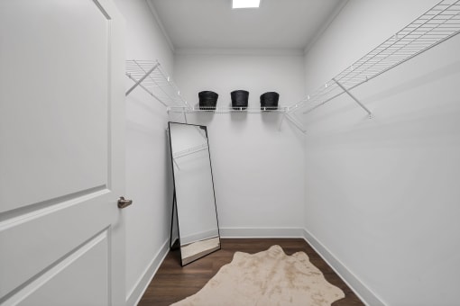 a walk in closet in a bedroom with white walls and a white door