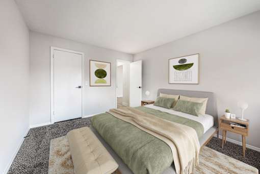 A bedroom with a bed, a couch, and two pictures on the wall.