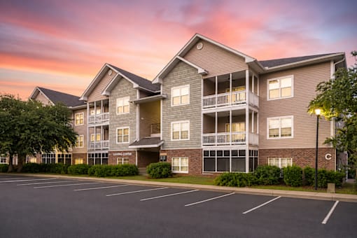 A large apartment complex with a parking lot in front.