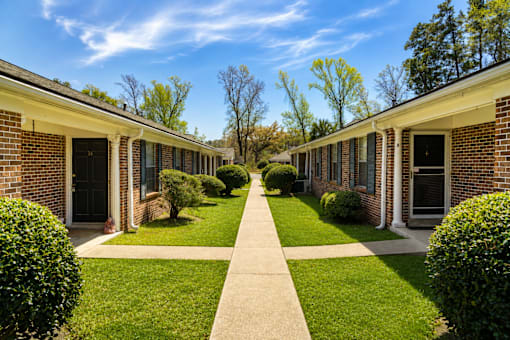 A long row of houses with green lawns and trees in the background.
