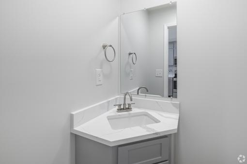 A white sink in a bathroom with a mirror above it.