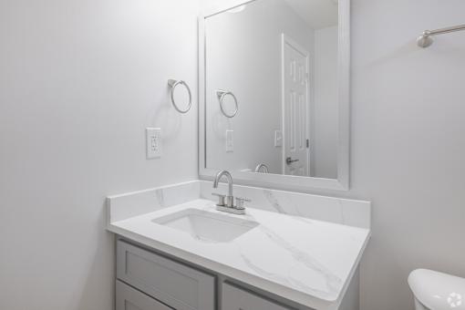 A white bathroom with a sink and mirror.