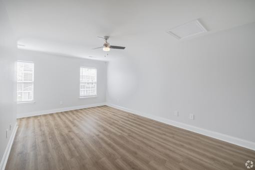 A room with a ceiling fan and wooden flooring.