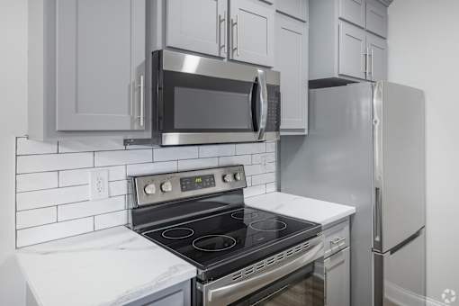 A modern kitchen with a stove, microwave, and refrigerator.
