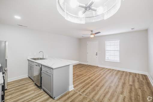 A kitchen with a white countertop and wooden flooring.