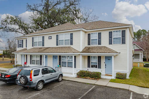 A two-story house with a blue door and a car parked in front.