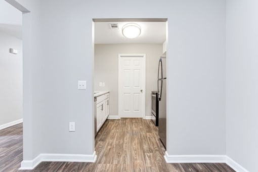 a renovated living room and kitchen with white walls and wood floors at Magnolia Place at Stockbridge Apartments, Stockbridge, GA