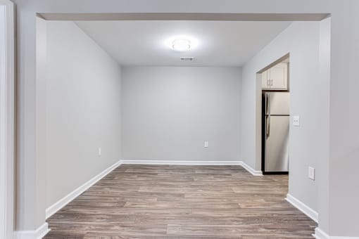 Dining room with white walls and wood flooring and a refrigerator at Magnolia Place at Stockbridge Apartments, Stockbridge