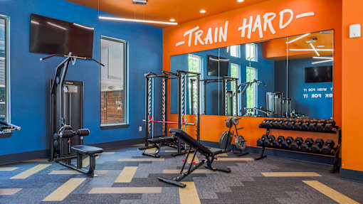 A gym with a blue and orange color scheme and a sign that says "TRAIN HARD".