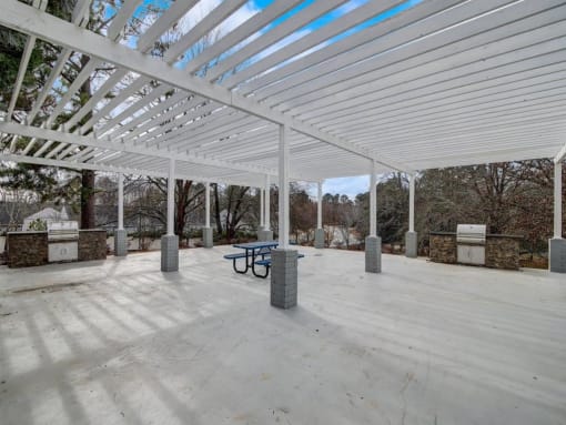 a covered patio with a table and a bench under a white roof  at The Sapphire, Decatur, GA