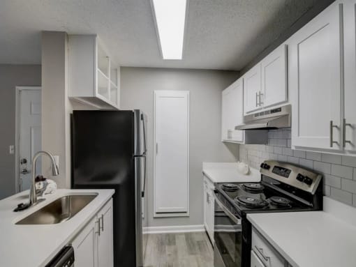 a kitchen with white cabinets and black appliances at The Sapphire, Decatur, Georgia