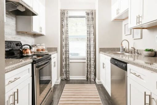 a kitchen with stainless steel appliances and white cabinets at The Sapphire, Decatur, Georgia