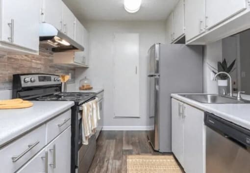 a white kitchen with stainless steel appliances and white cabinets at The Sapphire, Decatur, Georgia