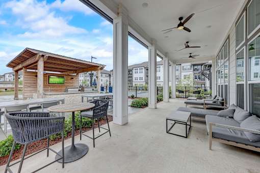 a patio with couches and tables and large windows at Century Mundy Mill Apartments, Georgia