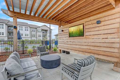 a patio with chairs and a table in front of a wooden house at Century Mundy Mill Apartments, Georgia 30566