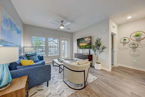 a living room with a couch and a chair and a ceiling fan at Century Mundy Mill Apartments, Oakwood