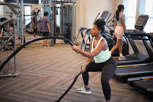 a woman in a gym using a resistance rope at Century Mundy Mill Apartments, Oakwood 30566