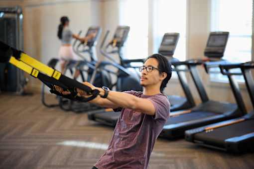 a young man exercising in a gym with a weights machine at Century Mundy Mill Apartments, Oakwood, Georgia