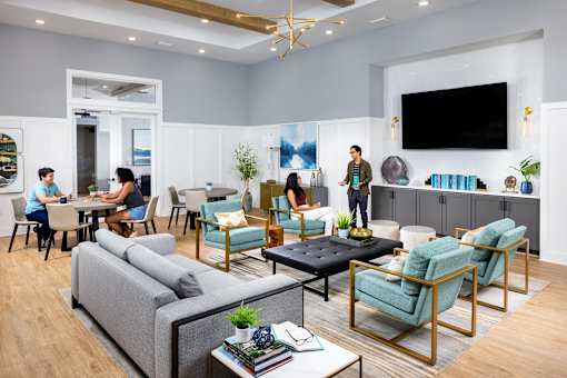 a living room with people sitting around a table and a tv at Century Mundy Mill Apartments, Oakwood, Georgia