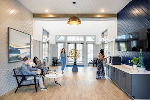 a group of people in an open living room with a kitchen at Century Mundy Mill Apartments, Georgia 30566