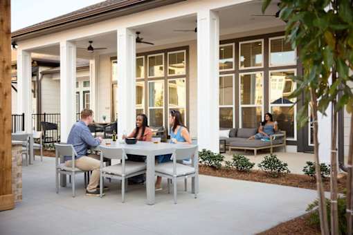 a group of people sitting around a table on a patio at Century Mundy Mill Apartments, Oakwood 30566