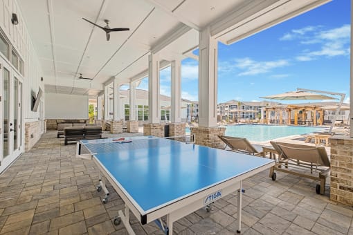 the pool area has a ping pong table and views of the pool and patio