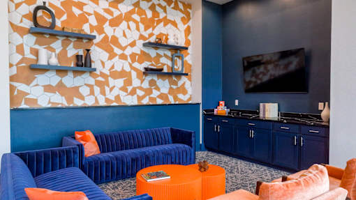 A living room with blue and orange furniture and a TV.