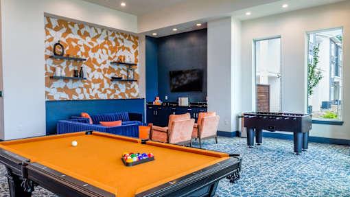 A pool table is in the middle of a room with a blue couch and a television.