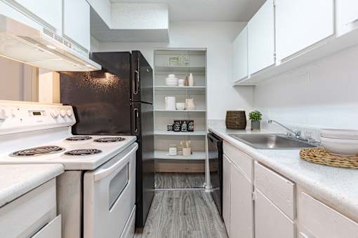 A modern kitchen with white appliances and a black refrigerator.