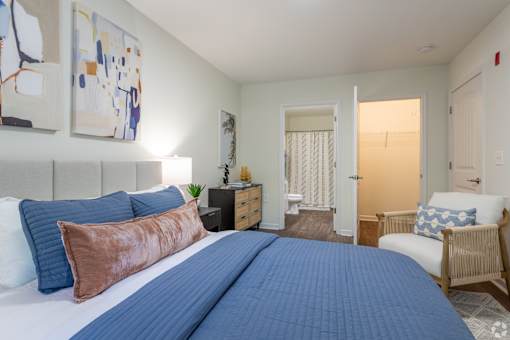 A bedroom with a large bed and a chair.