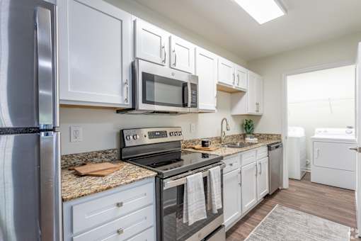 A kitchen with white cabinets and a granite countertop.