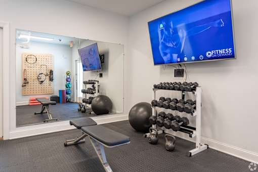 A gym room with a television screen showing a fitness program.