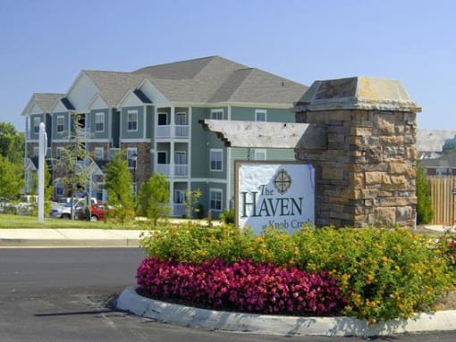 Entrance with flower beds and sign at The Haven at Knob Creek Apartments,