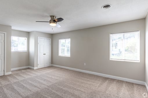 an empty bedroom with a ceiling fan and three windows at Summit Augusta, Augusta, GA 30909