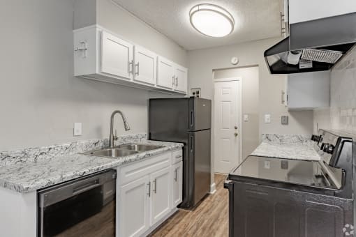 a kitchen with white cabinets and black appliances at Summit Augusta, Augusta